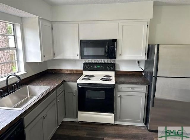 kitchen with white cabinets, a sink, a healthy amount of sunlight, dark wood-style floors, and black appliances
