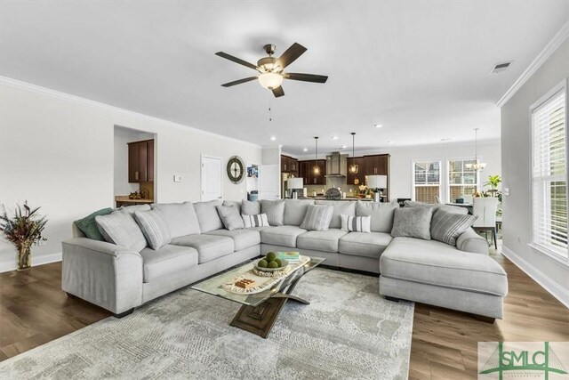52 Shoefstall St, Port Wentworth, GA 31407 - living room with ornamental molding, ceiling fan with notable chandelier, baseboards, visible vents, and wood finished floors