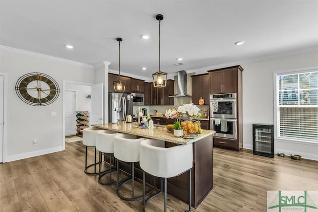 52 Shoefstall St, Port Wentworth, GA 31407 - kitchen featuring crown molding, stainless steel appliances, wine cooler, dark brown cabinets, and wall chimney exhaust hood