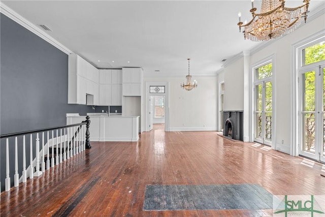417 Whitaker St, Savannah, GA 31401 - unfurnished living room featuring a chandelier, light wood finished floors, crown molding, a fireplace with raised hearth, and baseboards