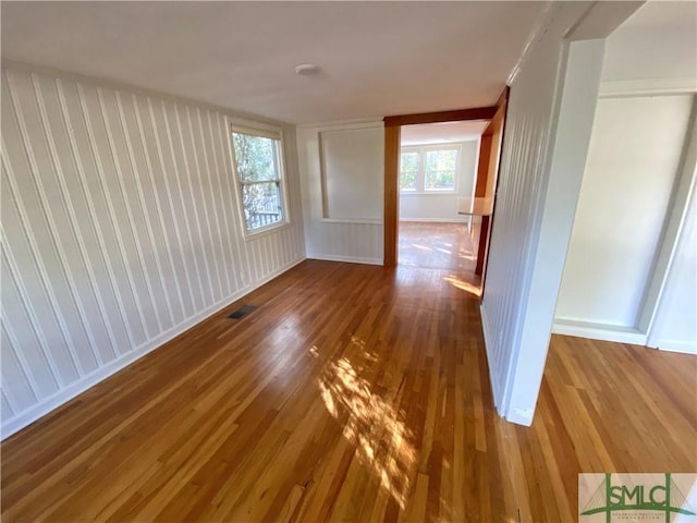 unfurnished room featuring visible vents, wood finished floors, and baseboards