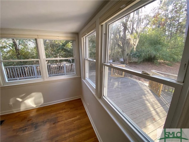unfurnished sunroom with a deck, visible vents, wood finished floors, and baseboards