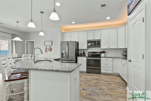 95 Glen Way, Richmond Hill, GA 31324 - kitchen featuring stainless steel appliances, a sink, light wood finished floors, backsplash, and white cabinets