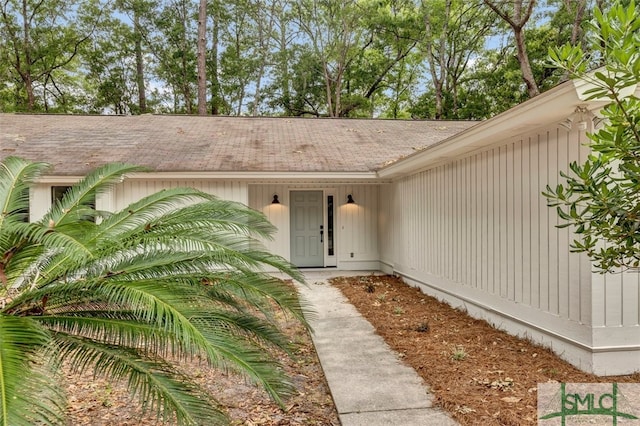 doorway to property with a shingled roof