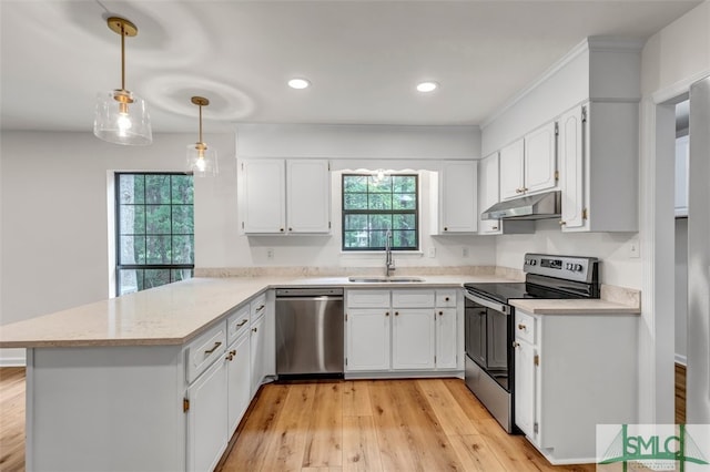 kitchen featuring a peninsula, a sink, a wealth of natural light, under cabinet range hood, and appliances with stainless steel finishes