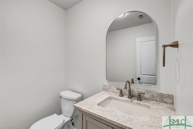 bathroom featuring toilet, vanity, and visible vents