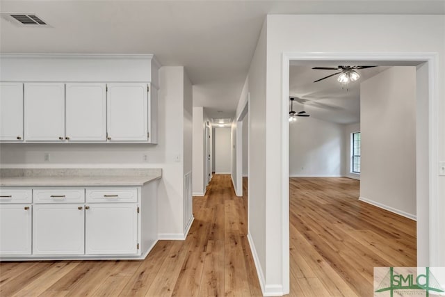 corridor with baseboards, visible vents, and light wood-style floors
