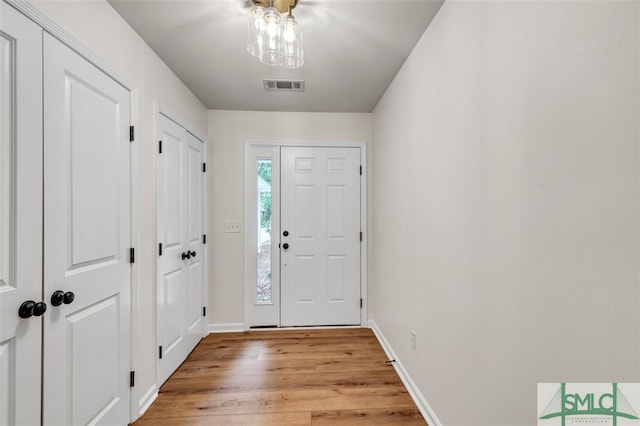 foyer entrance featuring baseboards, light wood finished floors, and visible vents