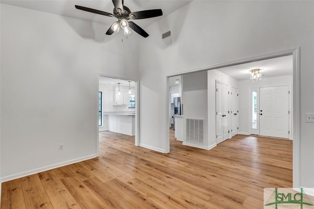 interior space featuring ceiling fan, baseboards, light wood finished floors, and visible vents