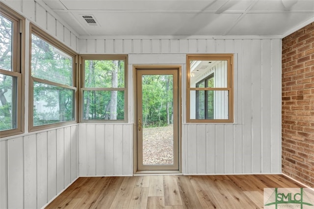 entryway with brick wall, light wood-style flooring, and visible vents