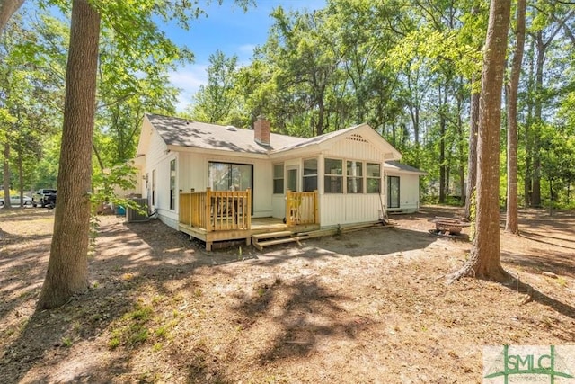 back of property featuring a wooden deck, a chimney, and an outdoor fire pit