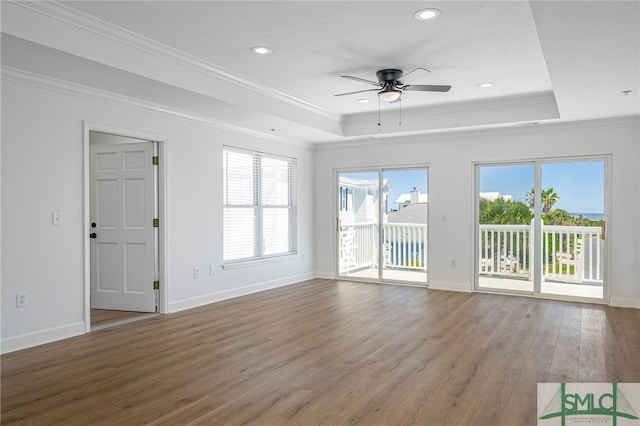 unfurnished living room featuring baseboards, crown molding, a ceiling fan, a raised ceiling, and wood finished floors