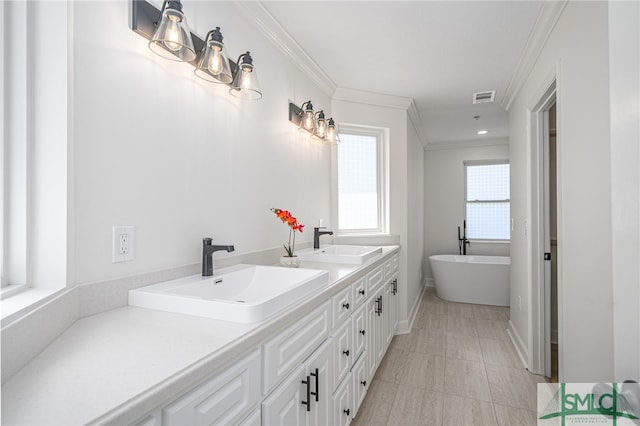 bathroom with a sink, visible vents, ornamental molding, and a freestanding tub