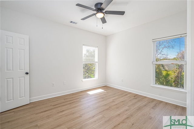 empty room with visible vents, light wood-type flooring, baseboards, and a ceiling fan