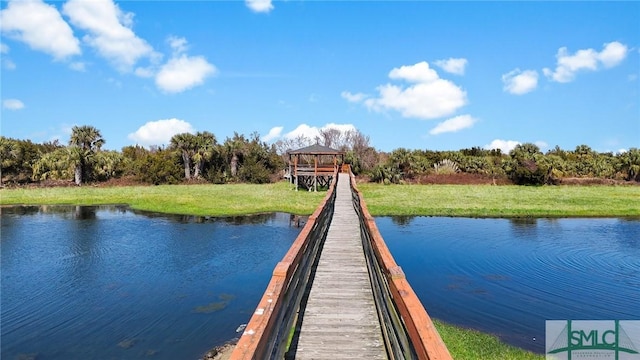view of dock with a water view and a yard