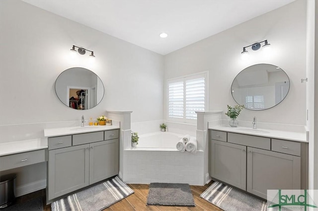 82 Rimmon Ct, Richmond Hill, GA 31324 - full bathroom with two vanities, wood finished floors, a sink, and a garden tub