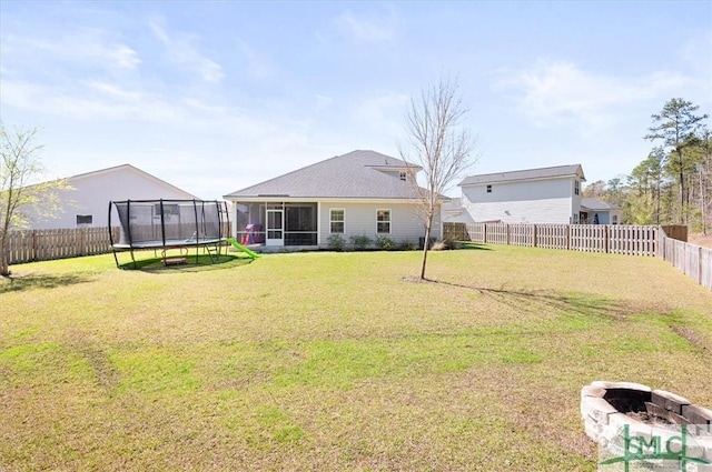 82 Rimmon Ct, Richmond Hill, GA 31324 - view of yard with a trampoline, a fenced backyard, a sunroom, and an outdoor fire pit