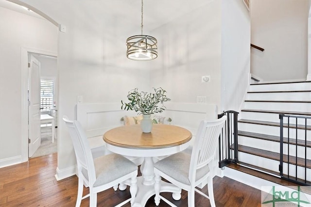 82 Rimmon Ct, Richmond Hill, GA 31324 - dining space featuring baseboards, wood finished floors, stairway, and an inviting chandelier