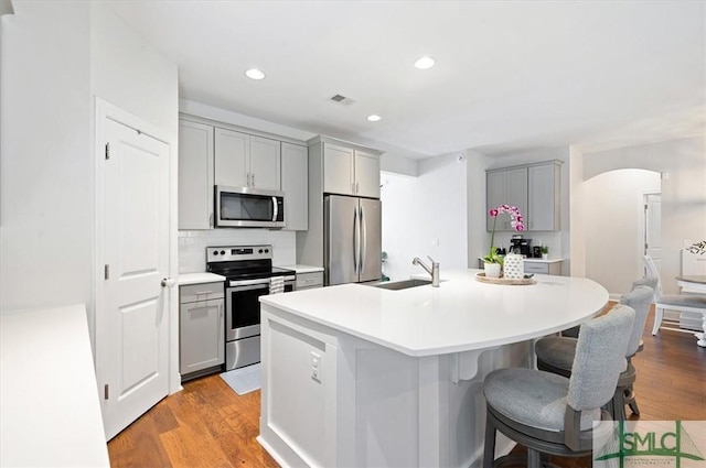 82 Rimmon Ct, Richmond Hill, GA 31324 - kitchen with light wood-style flooring, a breakfast bar, appliances with stainless steel finishes, an island with sink, and gray cabinetry