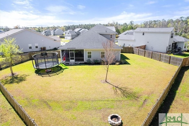 82 Rimmon Ct, Richmond Hill, GA 31324 - rear view of property featuring a fenced backyard, a lawn, a sunroom, and a trampoline