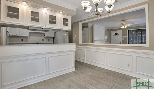 kitchen with freestanding refrigerator, light countertops, a decorative wall, and ornamental molding