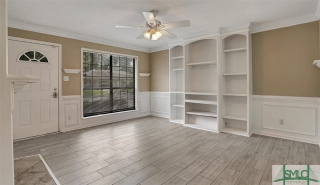 foyer with wood finish floors, ornamental molding, and ceiling fan