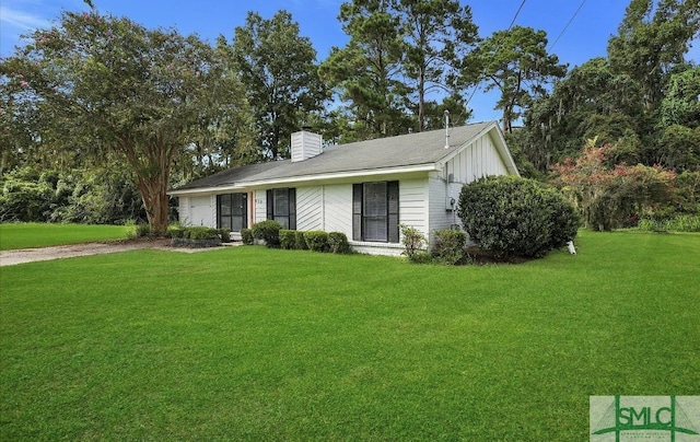 ranch-style home with a chimney, a front lawn, and board and batten siding