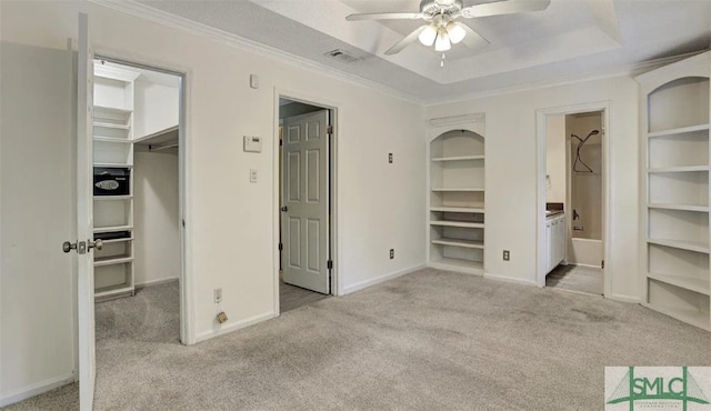 unfurnished bedroom featuring a closet, carpet floors, a tray ceiling, and a spacious closet