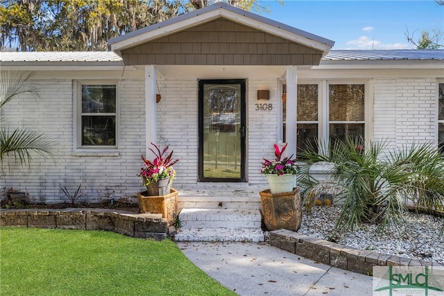 3108 Butler Ave, Savannah, GA 31404 - doorway to property with a yard, metal roof, and brick siding