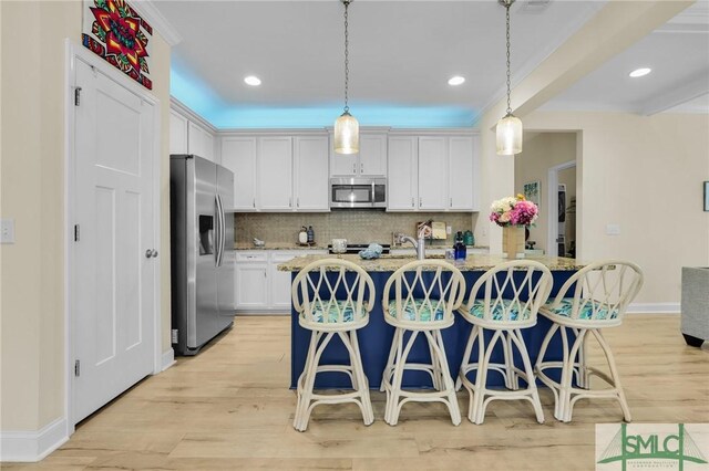 93 Bradford Pear Dr, Richmond Hill, GA 31324 - kitchen featuring stainless steel appliances, light wood-type flooring, backsplash, white cabinetry, and a kitchen breakfast bar