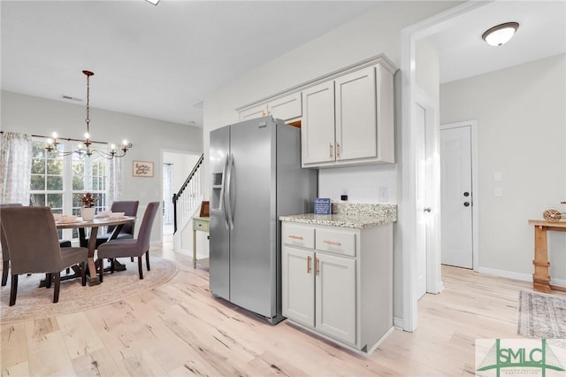 kitchen featuring an inviting chandelier, light wood-style flooring, stainless steel refrigerator with ice dispenser, and gray cabinets