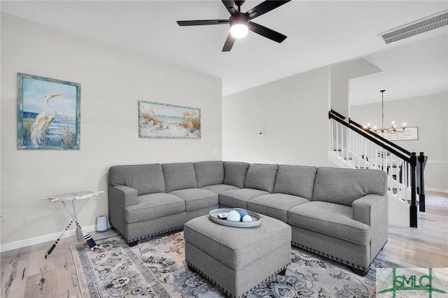 living room featuring visible vents, baseboards, stairs, wood finished floors, and ceiling fan with notable chandelier
