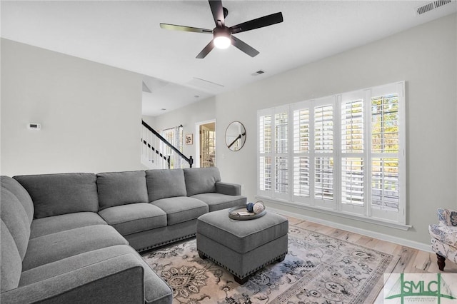 living room with stairs, visible vents, wood finished floors, and ceiling fan