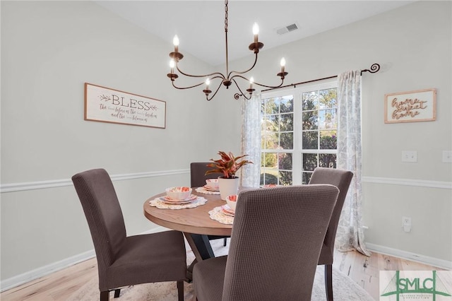 dining area with an inviting chandelier, wood finished floors, baseboards, and visible vents