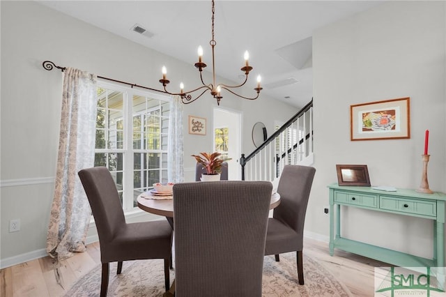 dining area featuring light wood-type flooring, a notable chandelier, baseboards, and visible vents