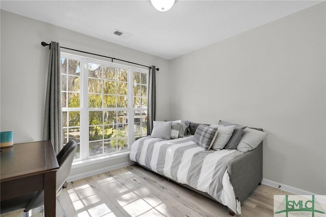 bedroom featuring baseboards, light wood-style floors, and visible vents