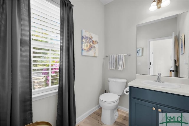 bathroom featuring toilet, vanity, baseboards, and wood finished floors