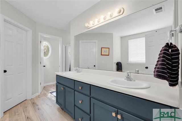 full bath featuring double vanity, a sink, wood finished floors, and visible vents