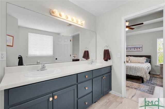 bathroom with ensuite bathroom, double vanity, a sink, and wood finished floors