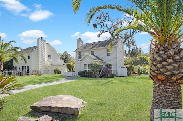 back of property with a chimney, fence, and a lawn