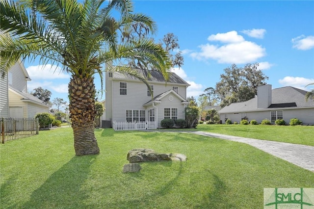 rear view of property with central AC, fence, and a lawn