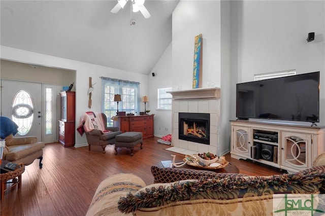 living room with high vaulted ceiling, baseboards, a ceiling fan, a fireplace, and wood finished floors