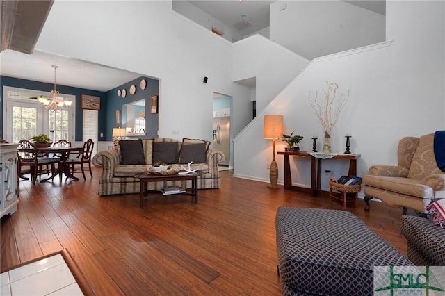 living area with an inviting chandelier, a high ceiling, and wood finished floors