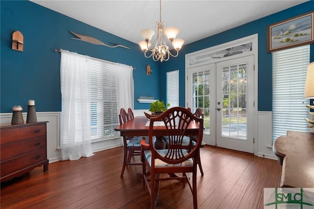 dining space featuring french doors, a wainscoted wall, a notable chandelier, and wood finished floors