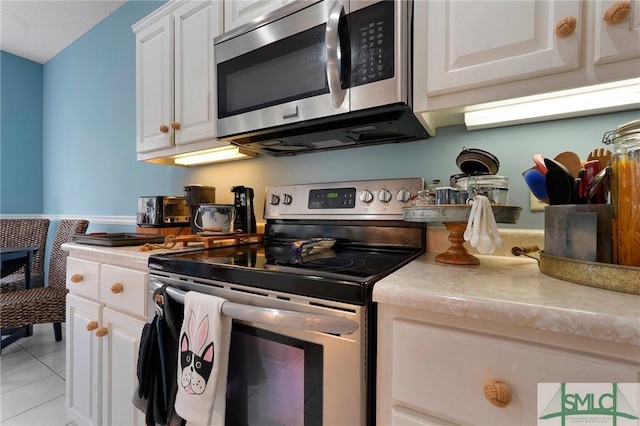kitchen with white cabinetry, light countertops, stainless steel appliances, and light tile patterned floors
