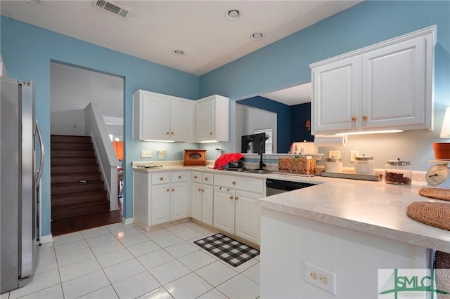 kitchen with light countertops, a peninsula, appliances with stainless steel finishes, and visible vents