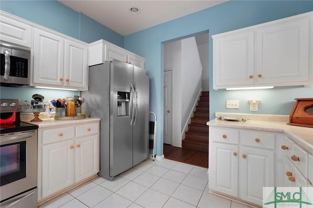 kitchen featuring white cabinetry, light countertops, light tile patterned flooring, and stainless steel appliances