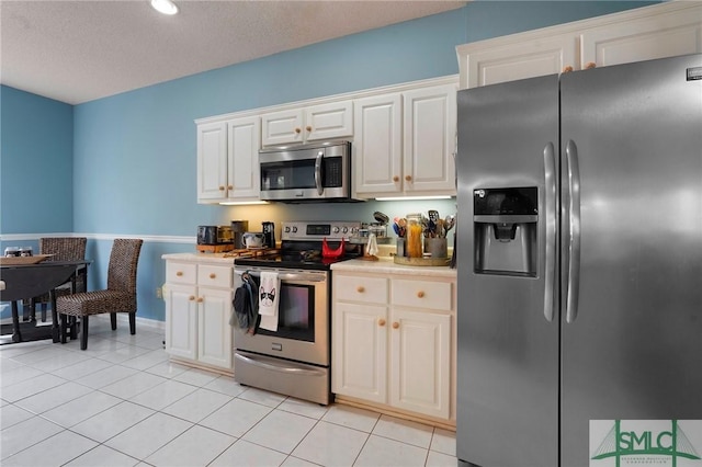 kitchen with light countertops, white cabinets, baseboards, appliances with stainless steel finishes, and light tile patterned floors
