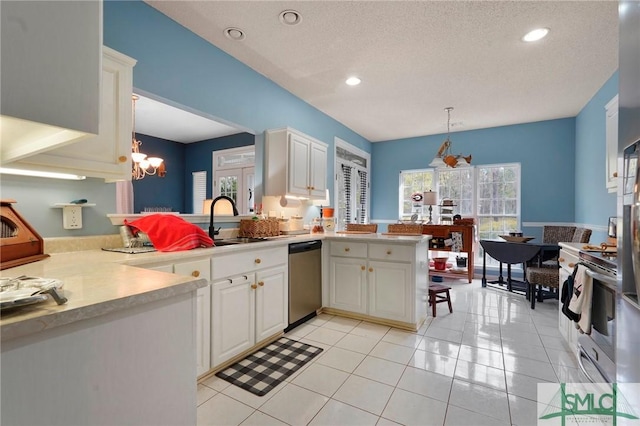 kitchen with light countertops, a notable chandelier, appliances with stainless steel finishes, white cabinetry, and light tile patterned floors