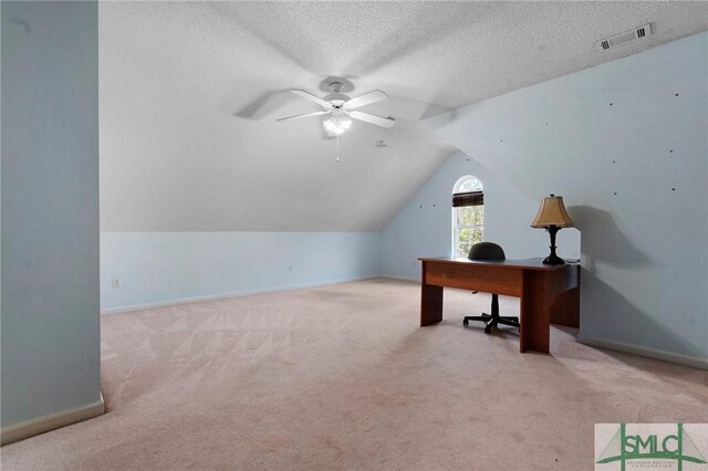 carpeted office featuring lofted ceiling, baseboards, a textured ceiling, visible vents, and a ceiling fan